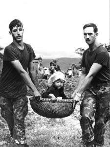 6th July 1970: Two American marines carrying a young Vietnamese refugee in a basket during the evacuation of a village near Da Nang. (Photo by Keystone/Getty Images)